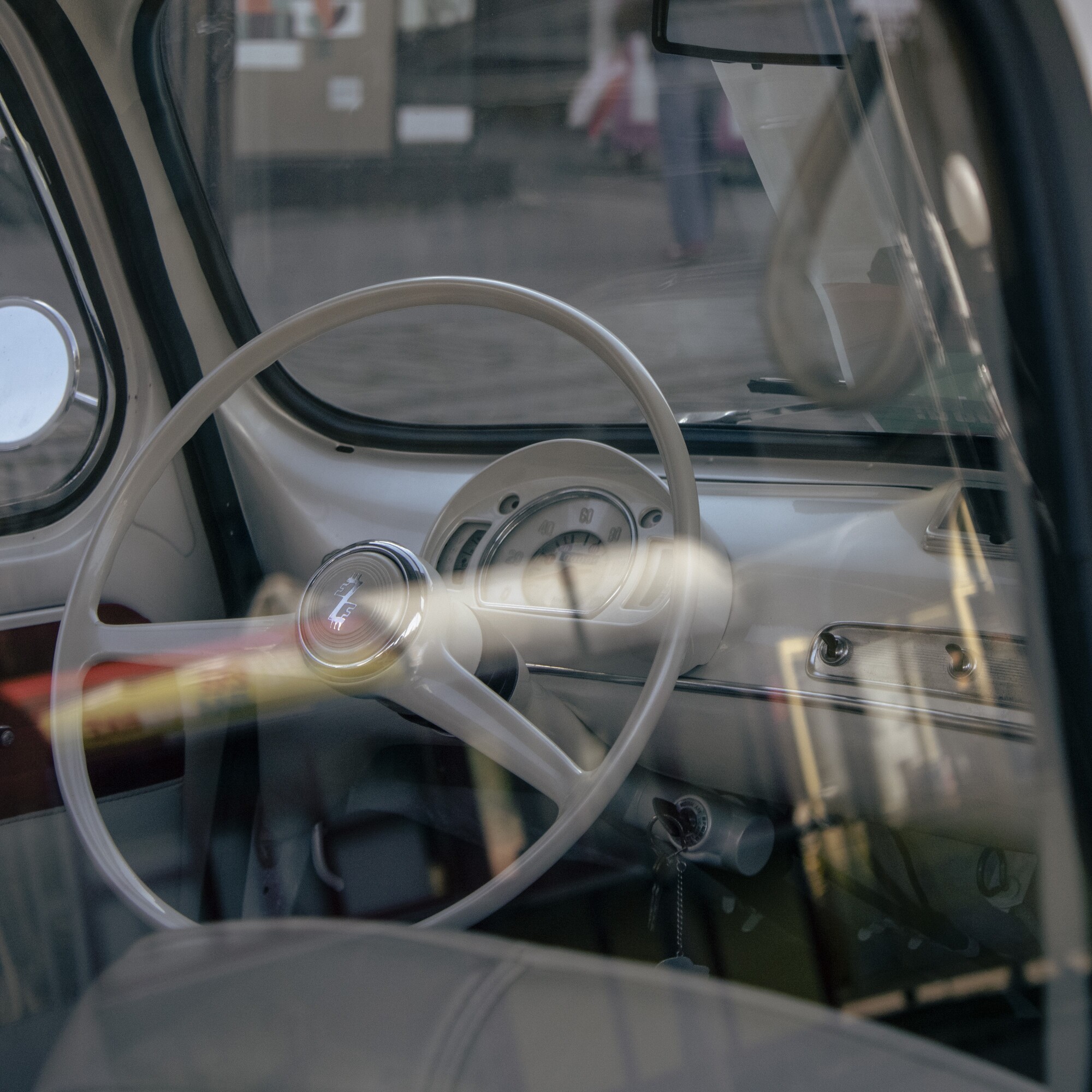 A vintage car interior with a classic steering wheel and dashboard, viewed through the window., by Vojislav Zivkovic aka Vojke Photo